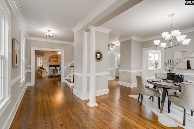 interior space featuring dark wood-type flooring, a chandelier, decorative columns, and crown molding