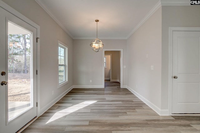 unfurnished dining area featuring light hardwood / wood-style floors, ornamental molding, and a chandelier