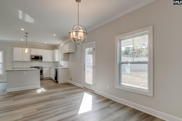 kitchen with appliances with stainless steel finishes, plenty of natural light, and white cabinetry