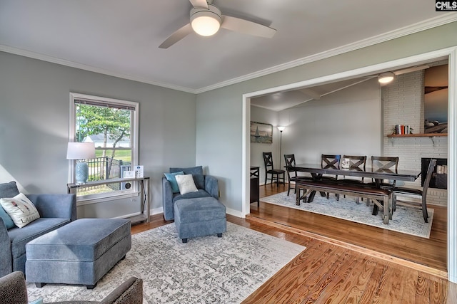 living room featuring hardwood / wood-style flooring, a brick fireplace, crown molding, and ceiling fan