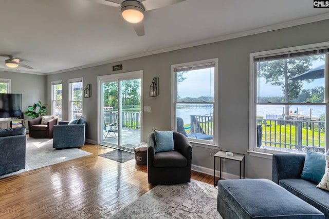 living room featuring ceiling fan, crown molding, wood-type flooring, and a water view