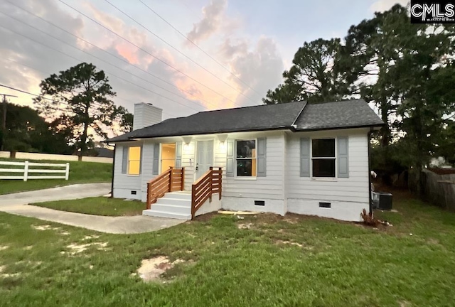 view of front of home with cooling unit and a yard