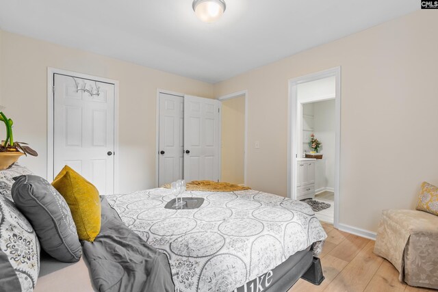 bedroom featuring light wood-type flooring, connected bathroom, and multiple closets