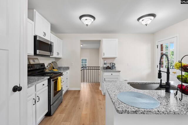 kitchen with sink, light stone countertops, light hardwood / wood-style floors, electric stove, and white cabinetry