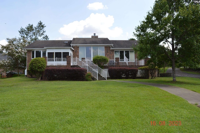 ranch-style home featuring a sunroom and a front lawn