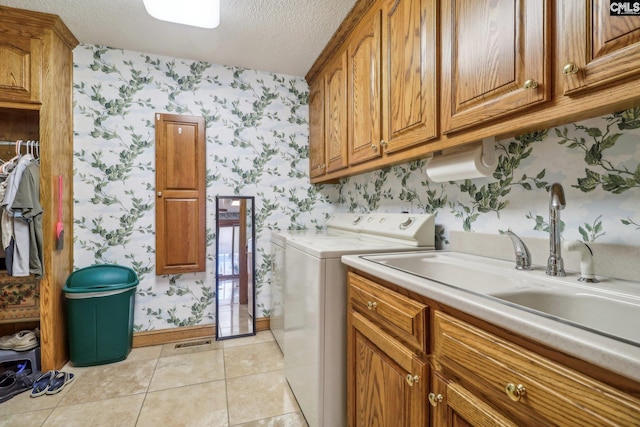 washroom featuring washing machine and dryer, cabinet space, a textured ceiling, and wallpapered walls