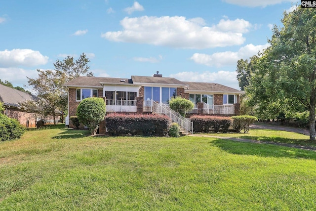 rear view of house with stairs, a lawn, and brick siding