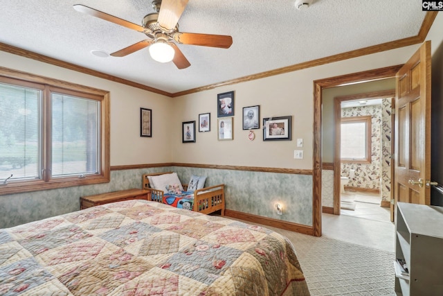 bedroom with wallpapered walls, multiple windows, a textured ceiling, and wainscoting