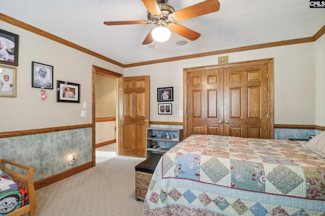 bedroom with a wainscoted wall, crown molding, a closet, light colored carpet, and a textured ceiling