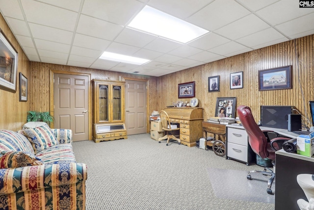 carpeted office with a paneled ceiling and wooden walls