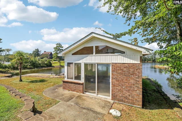 back of house featuring a water view, a lawn, and brick siding