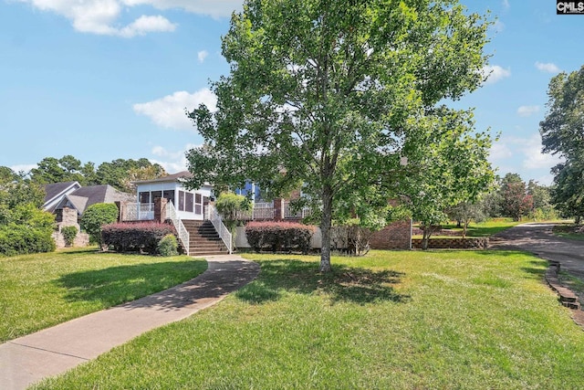 view of front of home with a front yard, stairway, brick siding, and a sunroom