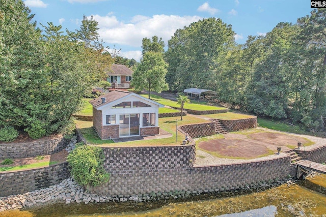 rear view of property with brick siding, a lawn, and a water view