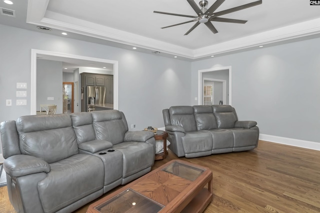 living room featuring visible vents, a raised ceiling, ceiling fan, and light wood-style flooring