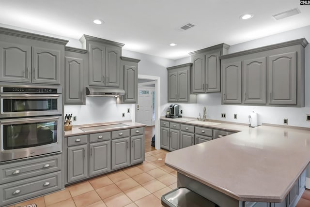 kitchen featuring double oven, black electric stovetop, a sink, under cabinet range hood, and gray cabinets