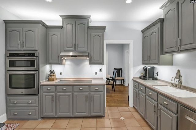 kitchen featuring gray cabinets, stainless steel appliances, light tile patterned floors, light countertops, and a sink