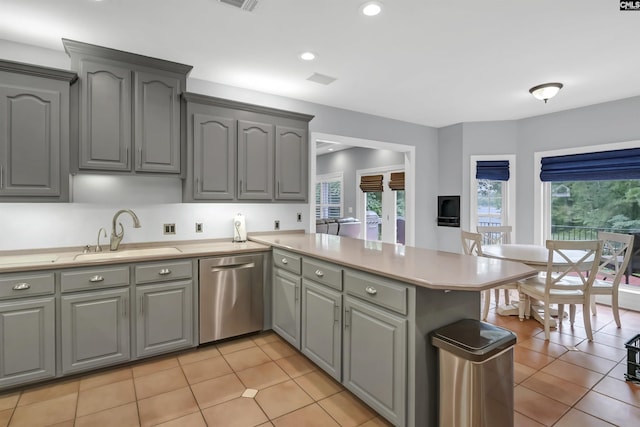 kitchen featuring a sink, dishwasher, a peninsula, and gray cabinets