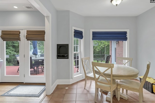 dining area featuring light tile patterned floors, a healthy amount of sunlight, visible vents, and baseboards