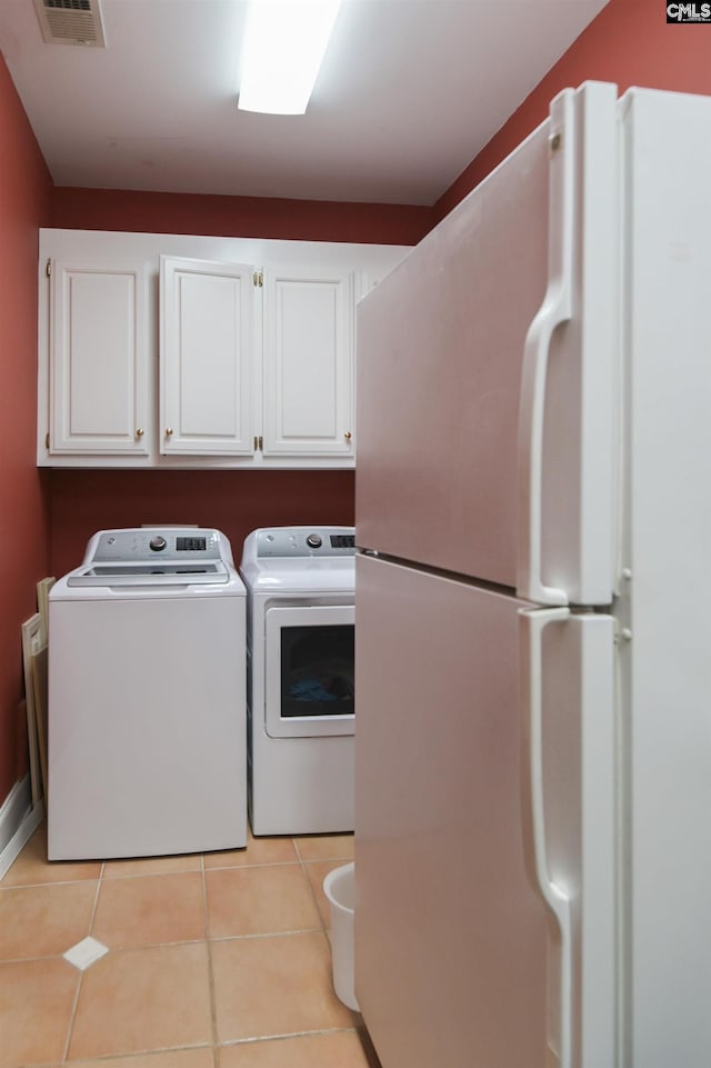 washroom with light tile patterned flooring, cabinet space, visible vents, and independent washer and dryer