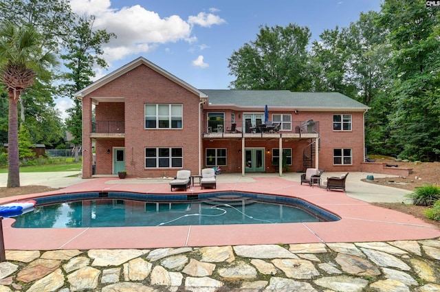 back of property featuring brick siding, an outdoor pool, and a patio area