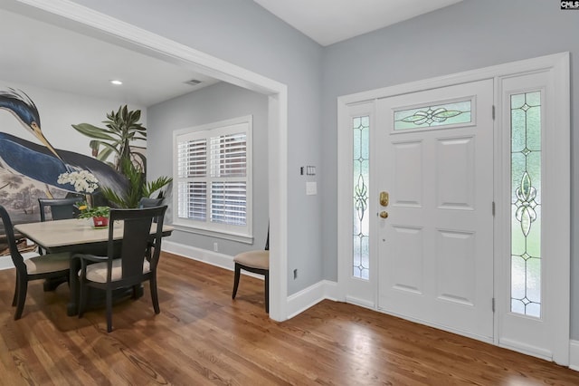 foyer with visible vents, wood finished floors, and baseboards