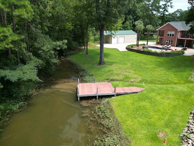 view of yard with a boat dock, an outdoor pool, a garage, and a water view