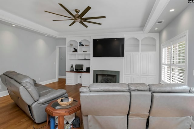 living room with a tray ceiling, ceiling fan, and hardwood / wood-style floors