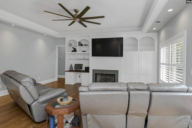 living room with visible vents, baseboards, wood finished floors, a ceiling fan, and built in shelves