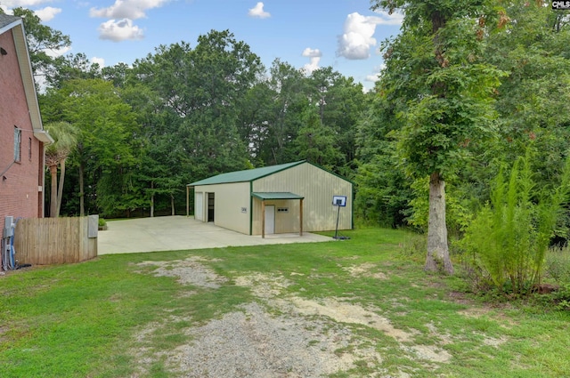 view of yard featuring driveway, a pole building, a detached garage, an outbuilding, and fence