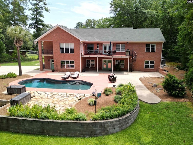 back of house with brick siding, a balcony, an outdoor pool, and a patio area