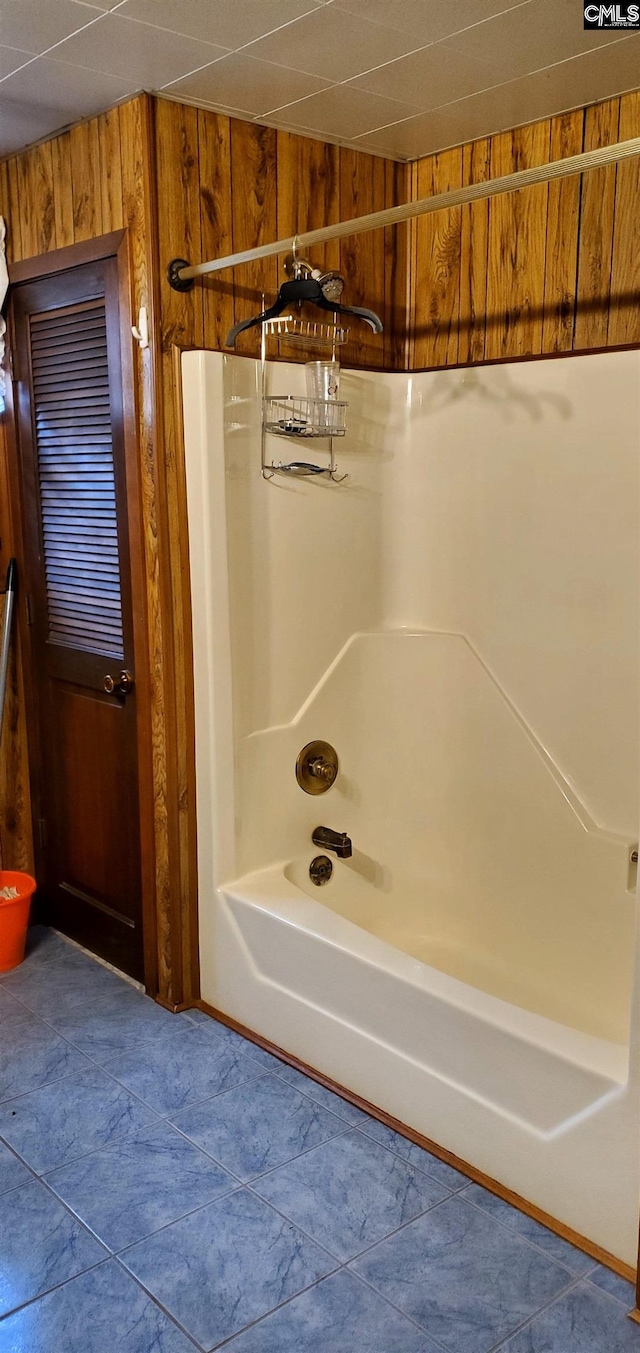 bathroom with wood walls and tub / shower combination