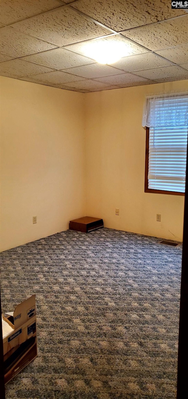 unfurnished room featuring a drop ceiling and dark carpet