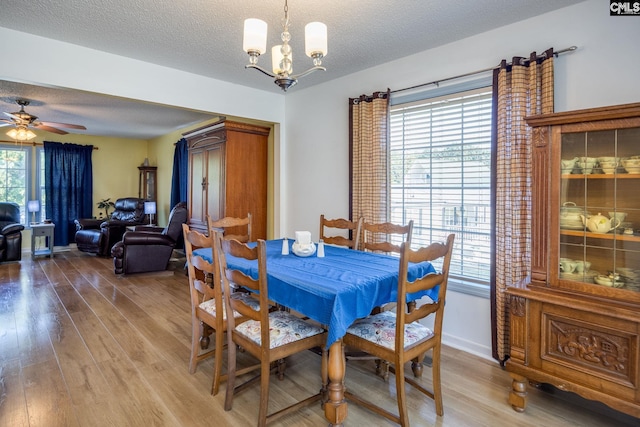 dining area featuring a textured ceiling, light wood-type flooring, and baseboards