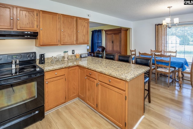 kitchen with a peninsula, under cabinet range hood, and black range with electric cooktop