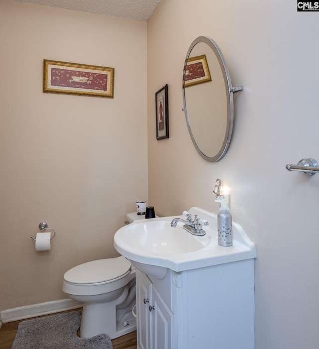 bathroom featuring toilet, vanity, and baseboards