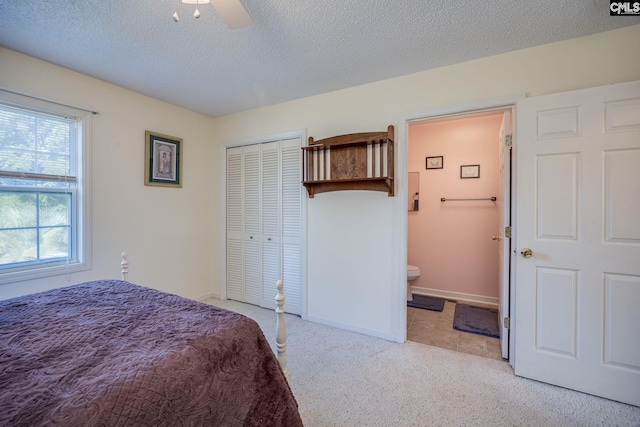 bedroom featuring a closet, light colored carpet, ensuite bathroom, a textured ceiling, and baseboards