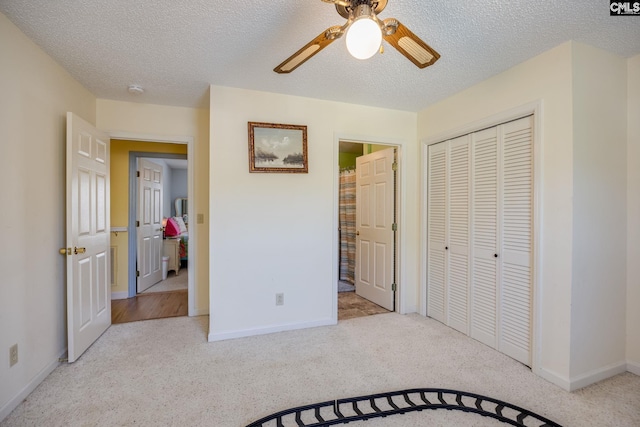 bedroom featuring ceiling fan, a textured ceiling, light carpet, baseboards, and a closet