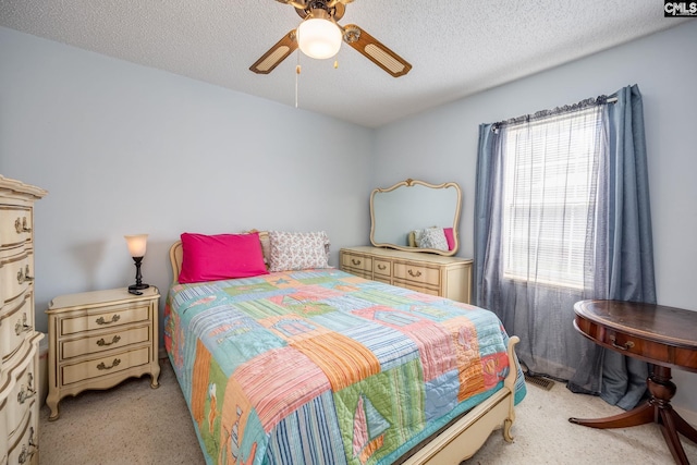 bedroom with a ceiling fan, light colored carpet, and a textured ceiling