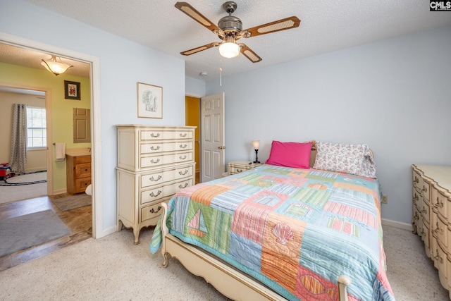 bedroom featuring ensuite bath, baseboards, a textured ceiling, and light colored carpet