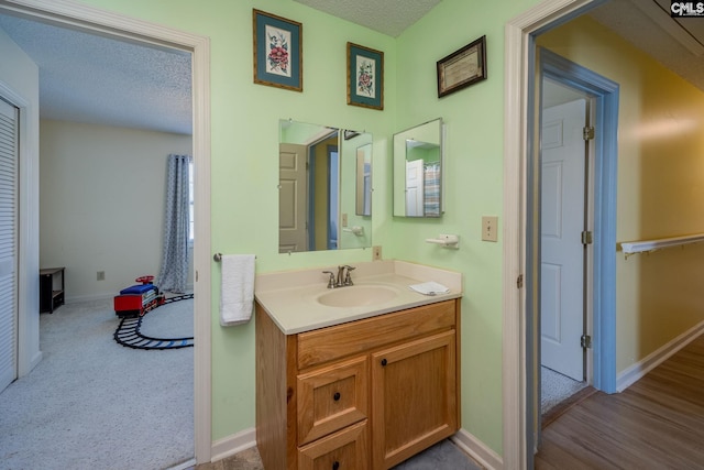 bathroom with a textured ceiling, vanity, and baseboards