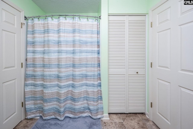 bathroom featuring a textured ceiling, a closet, and a shower with curtain