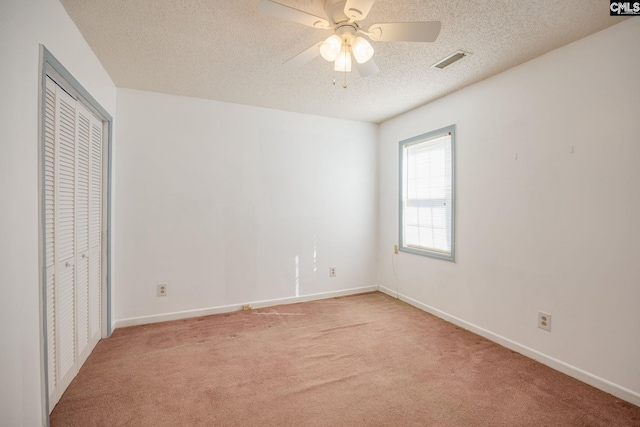 unfurnished bedroom featuring a closet, light colored carpet, visible vents, a textured ceiling, and baseboards