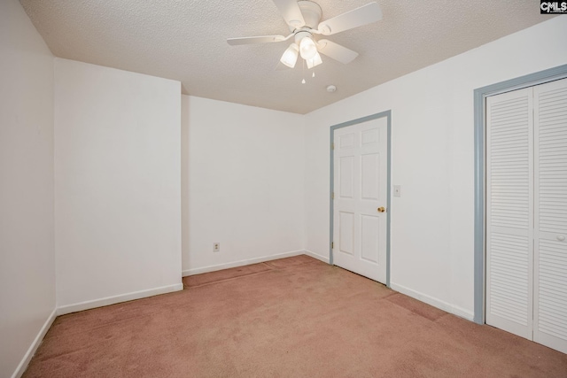 unfurnished bedroom with a closet, baseboards, a textured ceiling, and light colored carpet