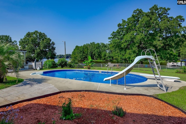 outdoor pool with a diving board, a water slide, and fence