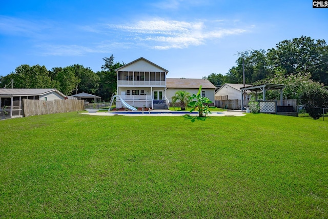 rear view of property with a fenced in pool, a yard, a sunroom, a pergola, and a fenced backyard