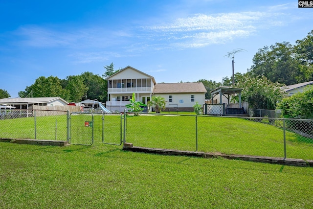 view of yard with a sunroom, a fenced backyard, and a gate