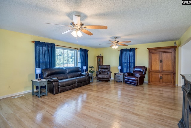 living room featuring a textured ceiling, light wood finished floors, and visible vents