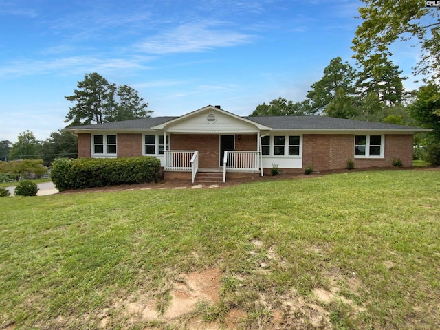 ranch-style house featuring a porch, a front lawn, and brick siding