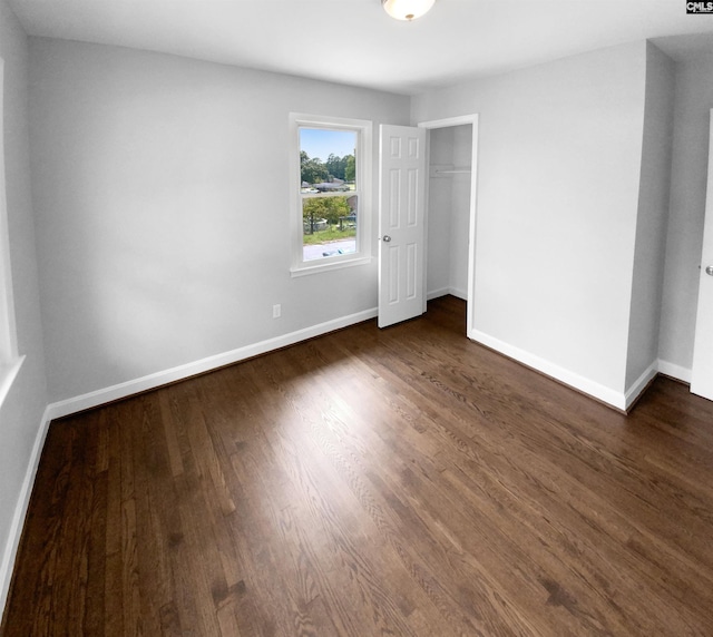 unfurnished bedroom with baseboards, dark wood finished floors, and a closet