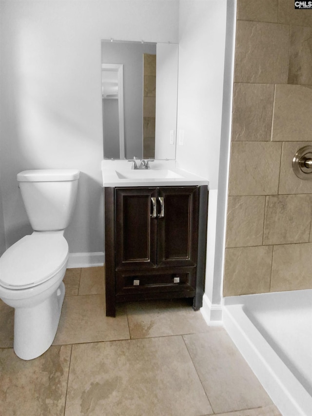 full bath featuring tile patterned flooring, toilet, vanity, baseboards, and a stall shower